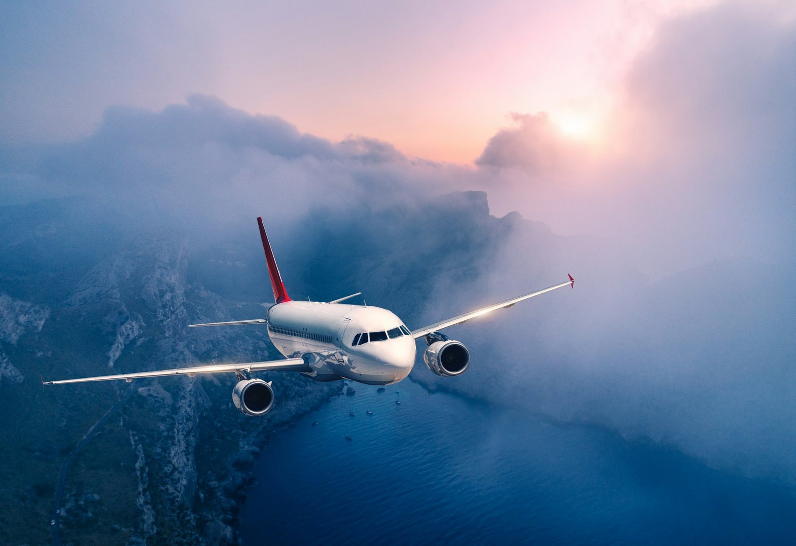 Passenger airplane is flying over clouds at sunset